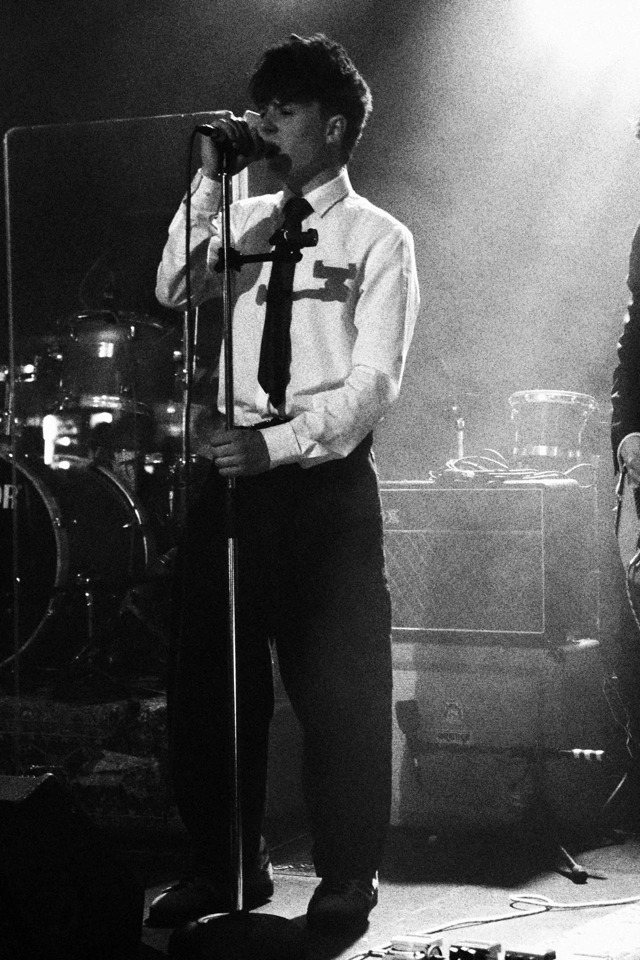 Kemlo at the mic stand in front of the drum kit